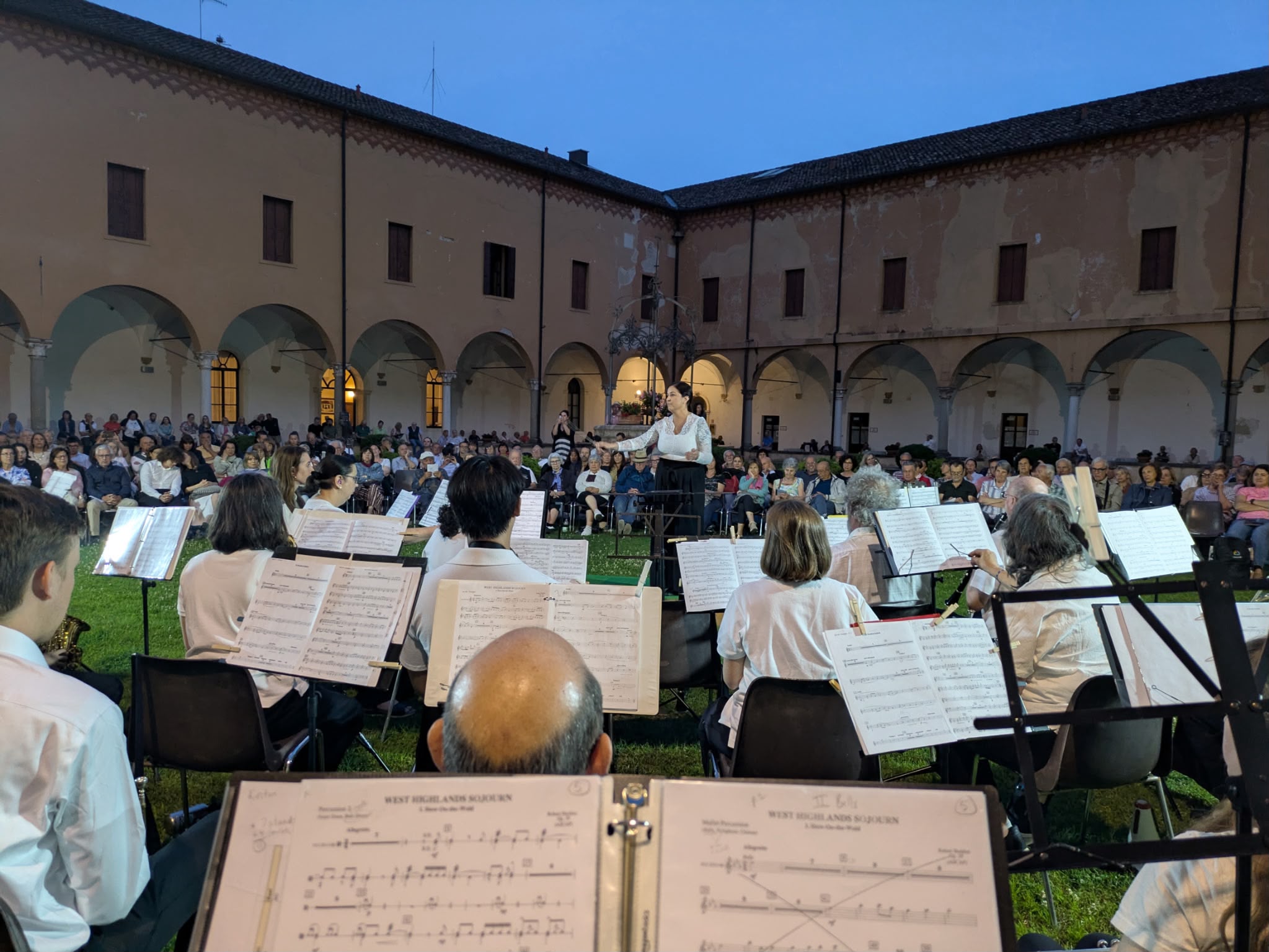 Katie McKee conducting the ensemble to a large outdoor audience in Italy